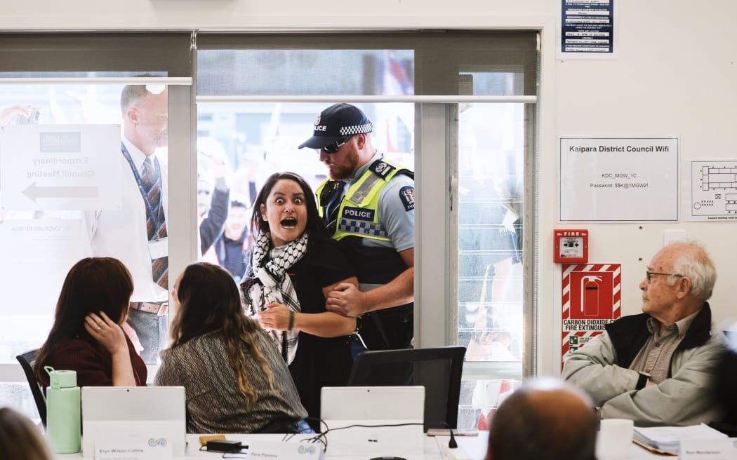 Protester Miharo Edwards expresses her views with a pukana in a Mangawhai meeting venue entranceway as KDC heads towards abolishing its Māori ward on Wednesday