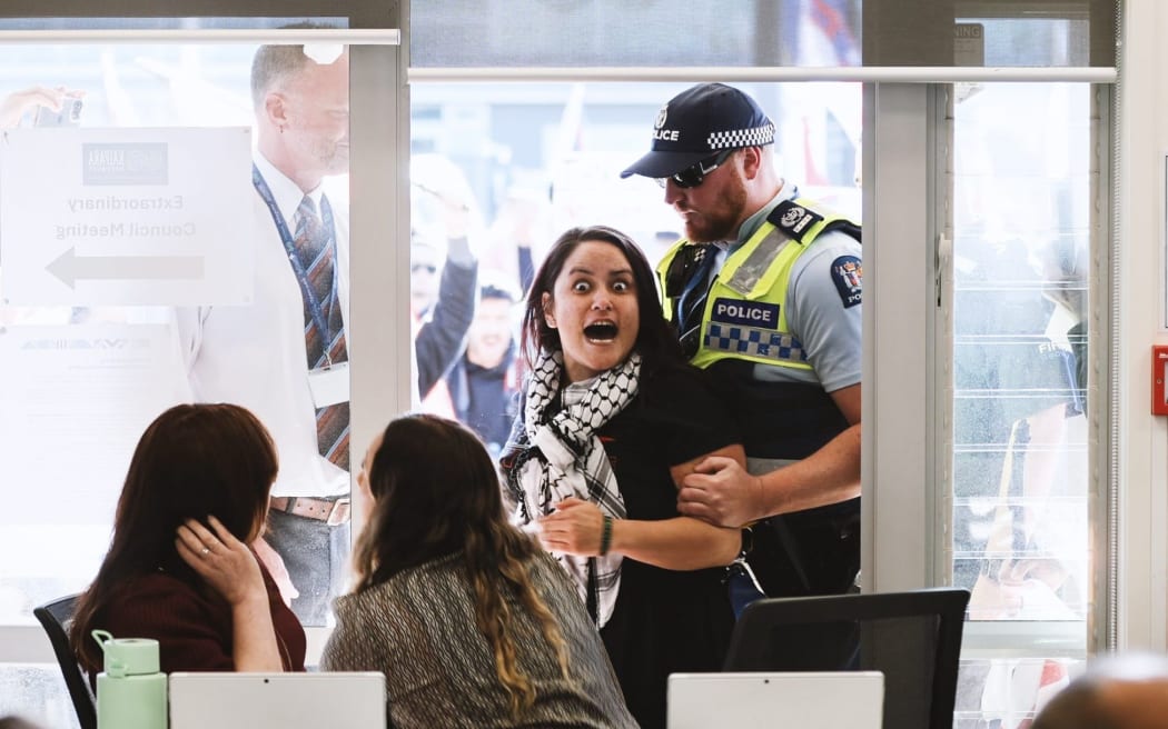 Protester Miharo Edwards expresses her views with a pukana in a Mangawhai meeting venue entranceway as KDC heads towards abolishing its Māori ward on Wednesday