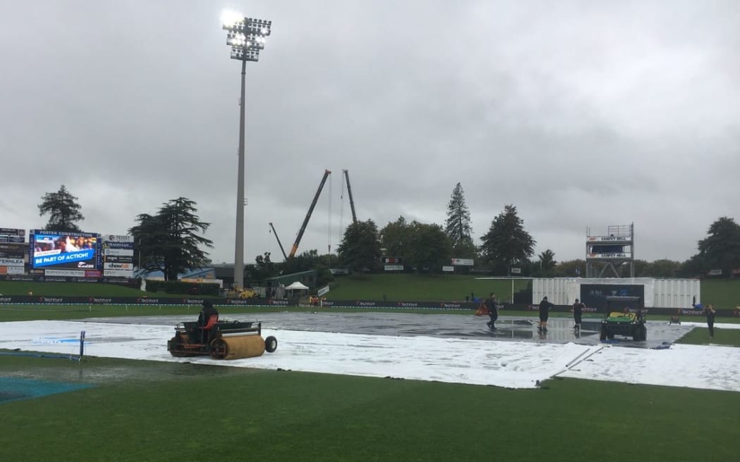 Ground staff attempt to dry out a waterlogged Seddon Park.