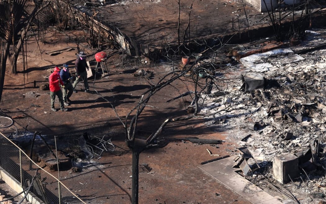 Search and rescue crews walk through a neighborhood that was destroyed by wildfire.