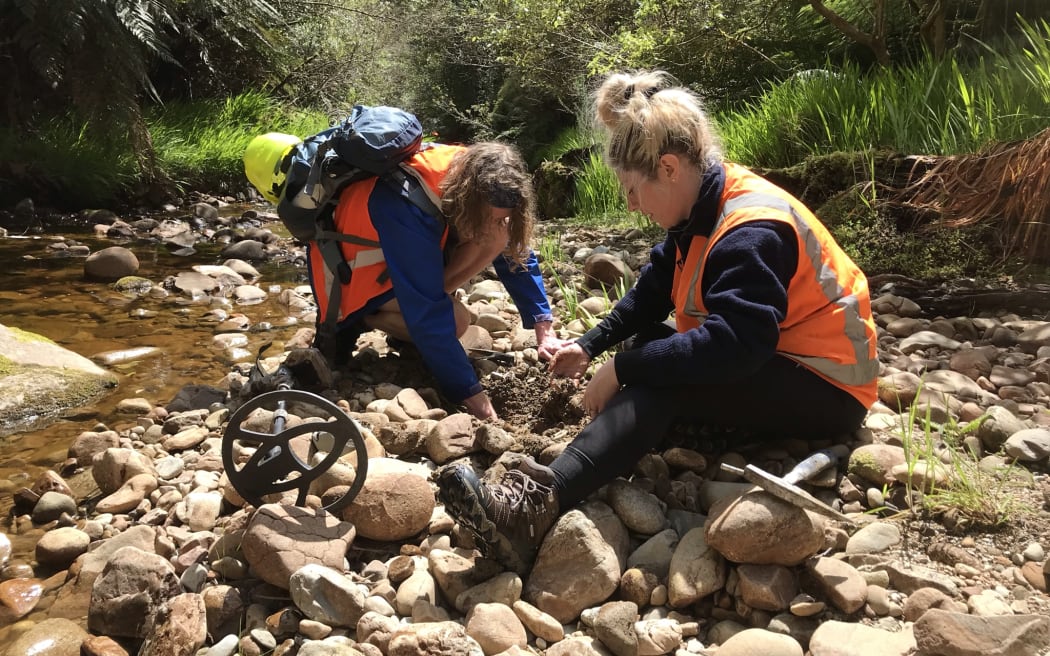 Daniel Burgin and Eve Aitken dig through the stones by the stream bed.