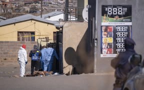 Members of the South African Police Service (SAPS) and forensic pathology services inspect the scene of a mass shooting in Soweto, South Africa, on July 10, 2022. - Fourteen people were killed during a shootout in a bar in Soweto police said on July 10, 2022.
Police lieutenant Elias Mawela said that they were called in the early hours in the morning, around 12:30am after the shooting overnight Saturday and Sunday.
When police arrived at the scene, 12 people were confirmed dead.
11 others were taken to hospital with wounds but two later died, raising the death toll to 14. (Photo by EMMANUEL CROSET / AFP)
