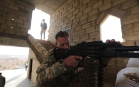 A Turkey-backed Syrian fighter sits behind a machine gun at a fortified position in Jarablus close to the border with Turkey in the rebel-held north of Syria's Aleppo province.