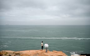 A man and a woman look out to the Taiwan strait at a tourist spot called "68 Nautical Miles" on Pingtan island, the closest point in China to Taiwan’s main island, in southeast China’s Fujian province on May 24, 2024. China warned on May 24 that Taiwan's leadership was pushing the self-ruled island into "a perilous situation of war and danger" and that it would go "further" if provoked, as Beijing conducted military drills around the territory. (Photo by Greg Baker / AFP)