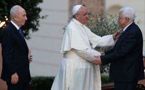 Pope Francis shakes hands with Palestinian leader Mahmoud Abbas as Israeli President Shimon Peres looks on.
