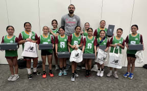 Steve Adams  behind presents the Rotorua U12 girls' basketball team with the new shoes they've just been given.