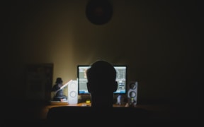 Male in front of a computer screen in the dark.