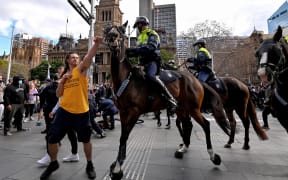 A protester (left) tries to push away a police horse in Sydney, as thousands of people gathered to demonstrate against the city's month-long stay-at-home orders.