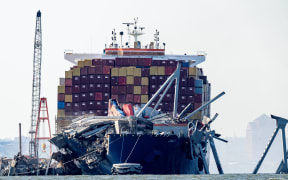 A section of the Francis Scott Key Bridge rests in the water next to the Dali container ship in Baltimore on 13 May, 2024 after crews conducted a controlled demolition. The Francis Scott Key Bridge, a major transit route into the busy port of Baltimore, collapsed on March 26 when the Dali container ship lost power and collided into a support column, killing six roadway construction workers.