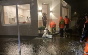 People fill sandbags at the Junction Cafe, on the corner of Hargest Crescent and Richardson Street, in St Clair.