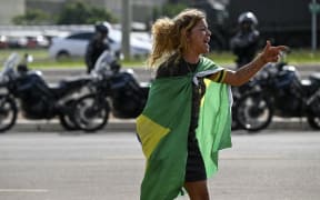 A demonstrator shouts at security forces while a camp set up by supporters of Brazil's far-right ex-president Jair Bolsonaro in front of the Army headquarters in Brasilia, is being dismantled by soldiers on January 9, 2023, a day after backers of the ex-president invaded the Congress, presidential palace and Supreme Court. - Brazilian security forces locked down the area around Congress, the presidential palace and the Supreme Court Monday, a day after supporters of ex-president Jair Bolsonaro stormed the seat of power in riots that triggered an international outcry. Hardline Bolsonaro supporters have been protesting outside army bases calling for a military intervention to stop Lula from taking power since his election win. (Photo by Mauro PIMENTEL / AFP)