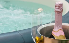 Detail view of luxury beautiful hot tub for relaxing, with decoration, towels, bottle of wine in nice interior.