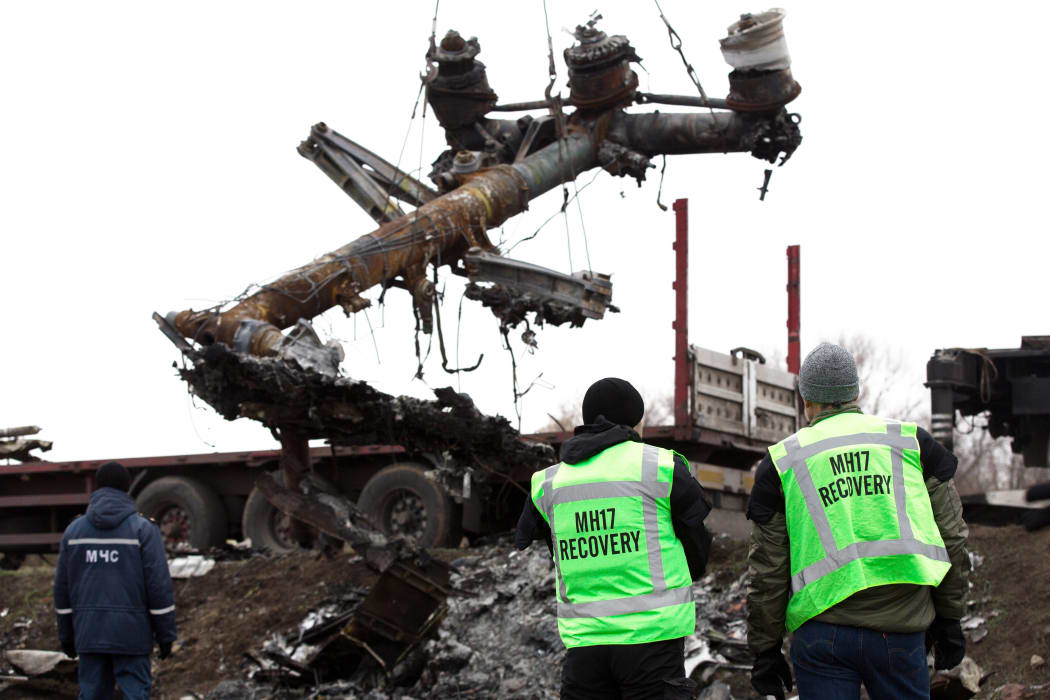 Members of the Dutch expert team watch as parts of the wreckage of the Malaysia Airlines Flight MH17 are removed.