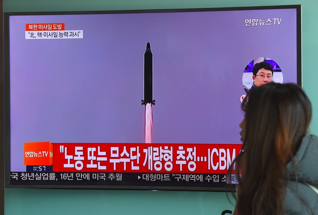 A woman walks past a television screen showing file footage of North Korea's missile launch at a railway station in Seoul on February 12, 2017.