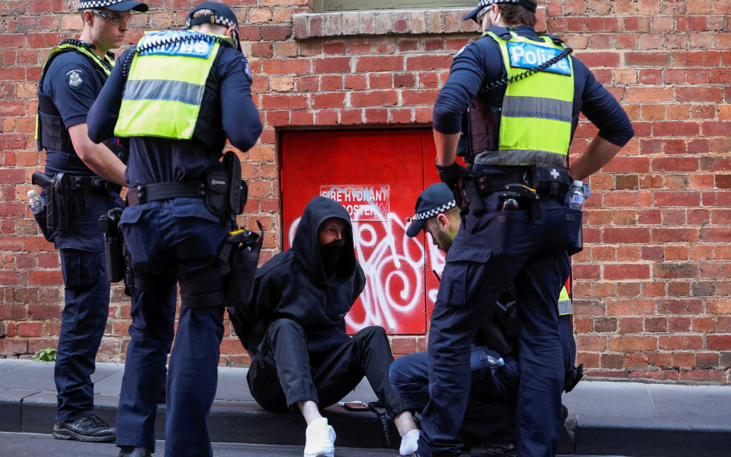 A protestor is arrested after attending a Stop Immigration Rally organised by The National Socialist Network outside of Parliament House in Melbourne on May 13, 2023. (Photo by Martin KEEP / AFP)