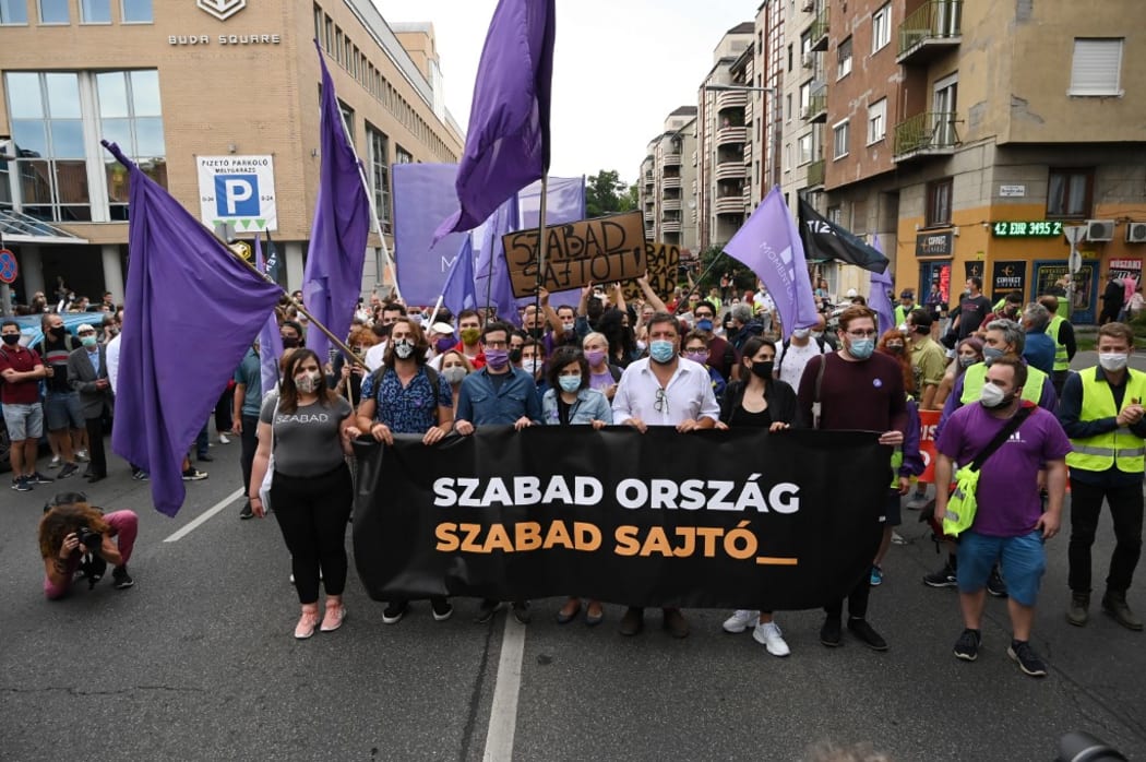 Activists and sympathizers of the centrist Hungarian political party 'Momentum Movement' hold a banner which reads "Free country, free press" as they march on the street beside the editorial building of 'Index'