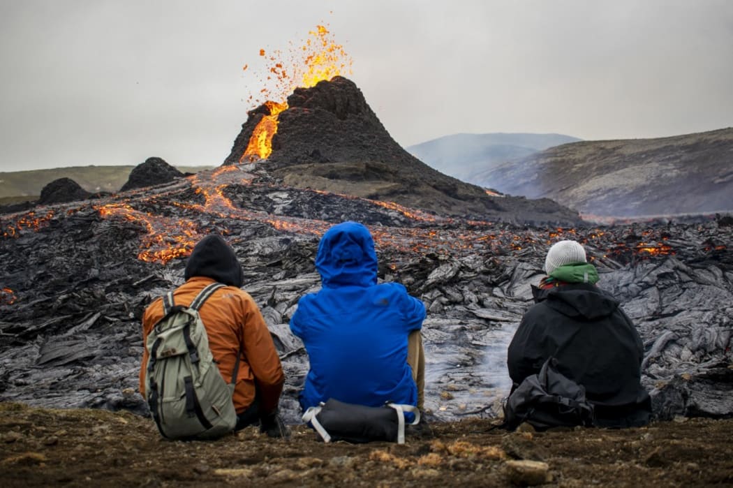 Sunday hikers look at the lava flowing from the erupting Fagradalsfjall volcano some 40 km west of the Icelandic capital Reykjavik.
