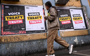 A woman walks past posters advocating for an Aboriginal voice and treaty ahead of an upcoming referendum, in Melbourne on August 30, 2023. Prime Minister Anthony Albanese announced Australia will hold a historic Indigenous rights referendum on October 14 setting up a defining moment in the nation's relationship with its Aboriginal minority. (Photo by William WEST / AFP)