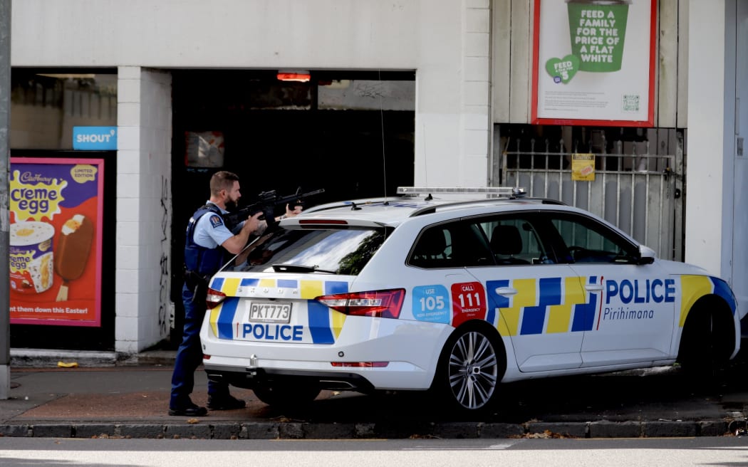 A police officer stands guard at a large police presence on Hobson Street.