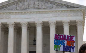 A demonstrator holds a sign reading 'regulate guns not my body' during a rally and silent protest demanding reproductive rights and voting rights outside of the Supreme Court in Washington, D.C. on May 25, 2022 (Photo by Bryan Olin Dozier/NurPhoto) (Photo by Bryan Olin Dozier / NurPhoto / NurPhoto via AFP)