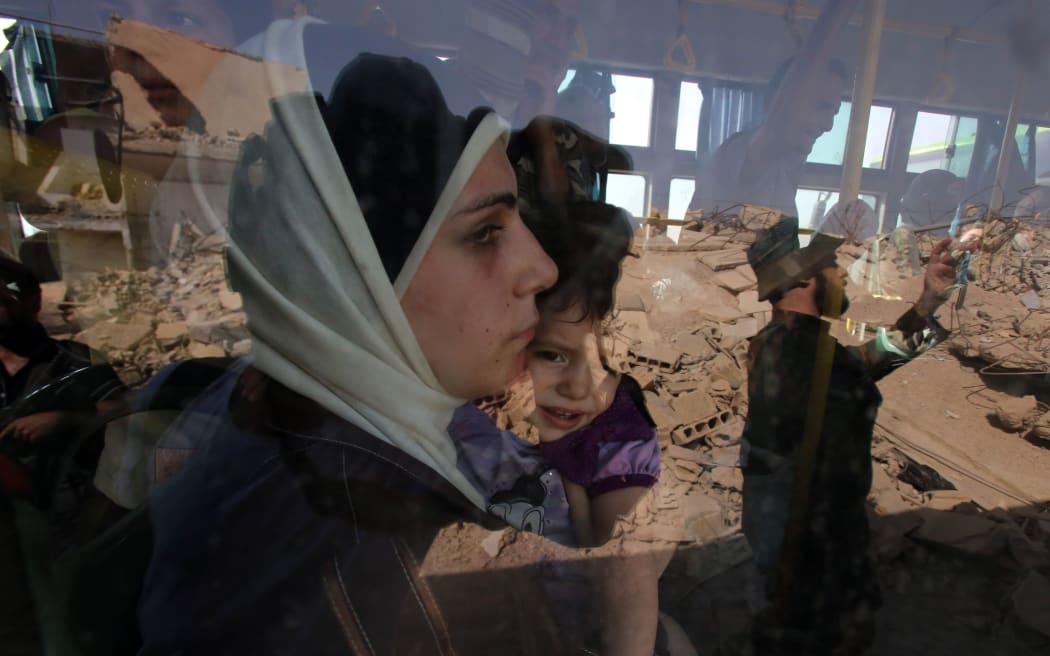 A woman and child are evacuated by bus from Darayya outside the Syrian capital.