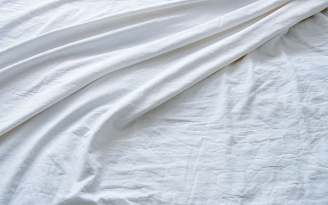 Top view of wrinkles on an unmade bed sheet after waking up in the morning.
