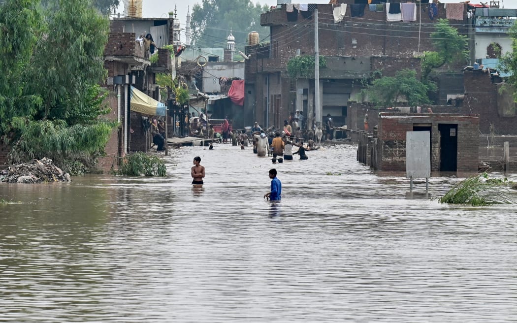 Residents wade through a flooded area of Kartarpur, a town in Punjab province, on 28 August, 2025.