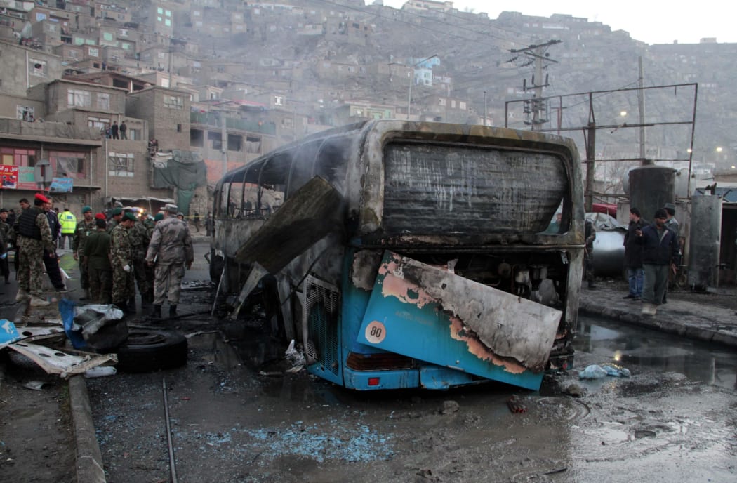 Afghan security personnel inspect a damaged bus at the site of a suicide attack by the Taliban in Kabul, Afghanistan.