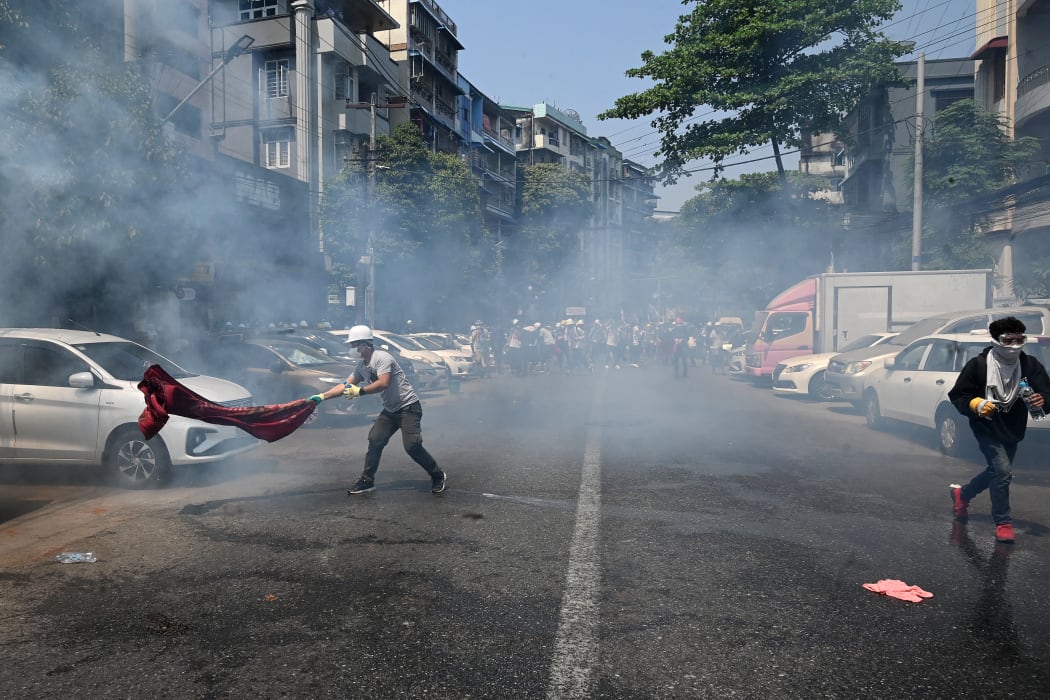 Protesters run after police fired tear gas to disperse them during a demonstration against the military coup in Yangon on 28 February