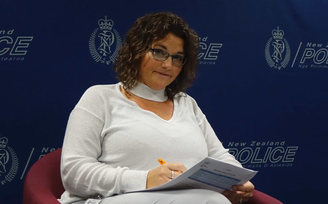 Head and shoulders of a woman in front of police signage
