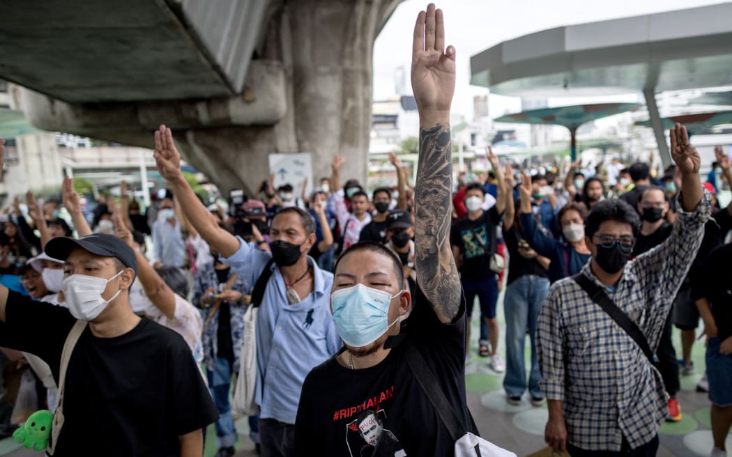 Protesters hold up the three-finger salute during a demonstration in Bangkok on September 30, 2022, after Thailand's Constitutional Court ruled that suspended prime minister Prayut Chan-O-Cha can continue in his role. (Photo by Jack TAYLOR / AFP)