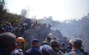 Rescuers gather at the site of a plane crash in Pokhara on January 15, 2023. - An aircraft with 72 people on board crashed in Nepal on January 15, Yeti Airlines and a local official said. (Photo by Yunish Gurung / AFP)