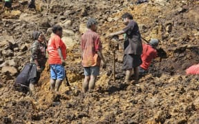 Locals dig during search and rescue efforts at the site of a landslide at Yambali village in the region of Maip Mulitaka in Papua New Guinea's Enga Province on May 30, 2024. Survivors of a deadly Papua New Guinea landslide face a "significant risk of disease outbreak" and are yet to receive sufficient food and clean water supplies, a United Nations agency said on May 30. Six days after a mountainside community was buried in a sea of soil, boulders and debris, the United Nations' migration agency said water sources had become tainted and the risk of disease was soaring. (Photo by Emmanuel Eralia / AFP)