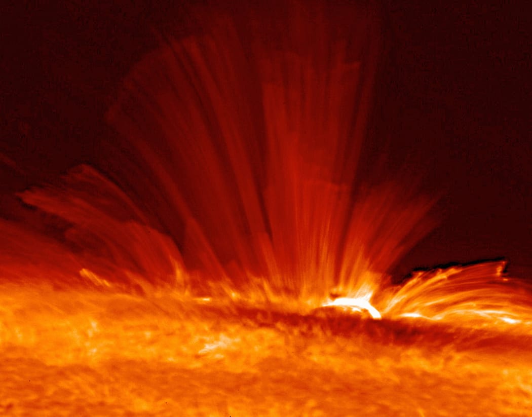 Sunspot with streamers of super-hot, electrically charged gas (plasma) arc from the surface of the Sun, revealing the structure of the solar magnetic field.
