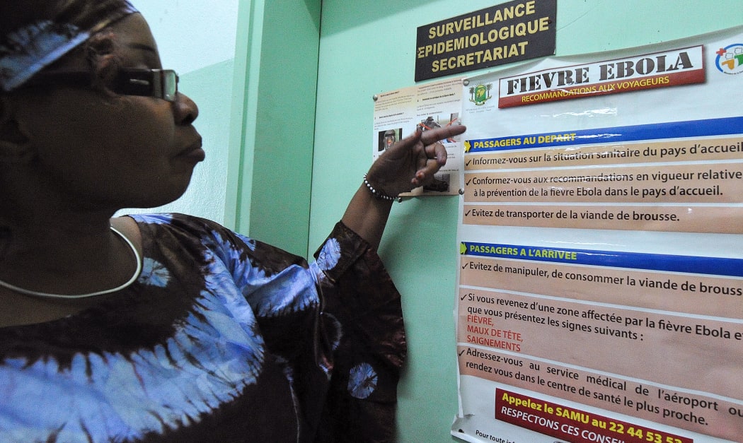 A woman reads Ebola warnings for travellers on the Ivory Coast  as the WHO declares the killer virus  an international health emergency.