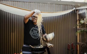 Muthuvelu Supramaniam puts noodles into a wok.