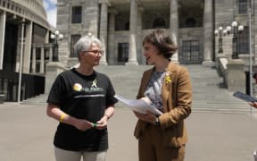 Corinda Taylor presents a petition with 55,000 signatures to Chlöe Swarbrick on the steps of parliament
