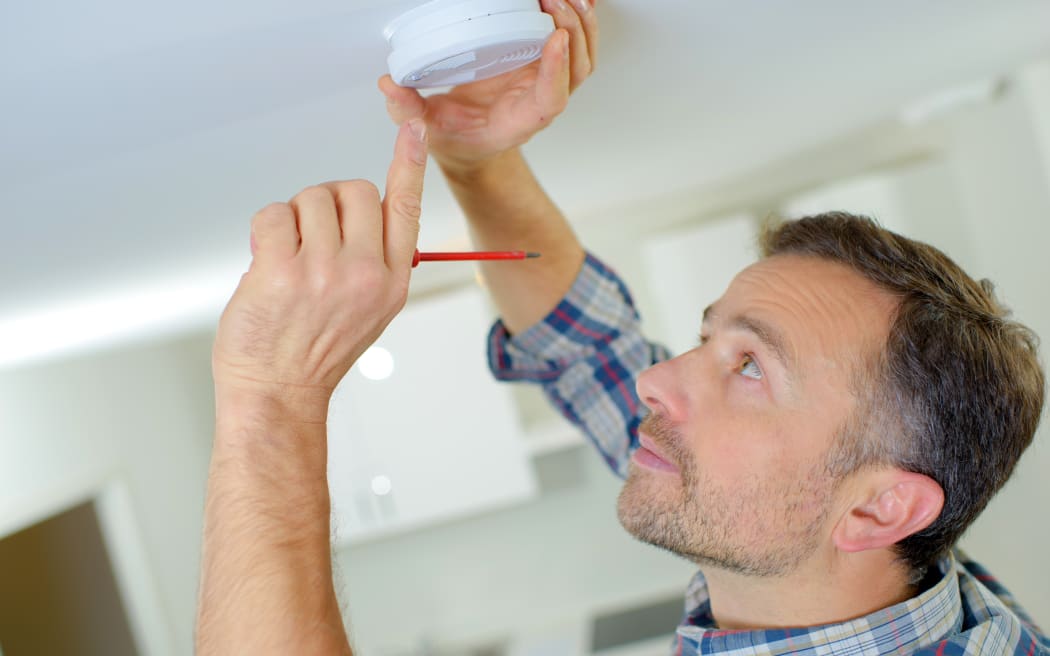 File image of man installing a smoke alarm.