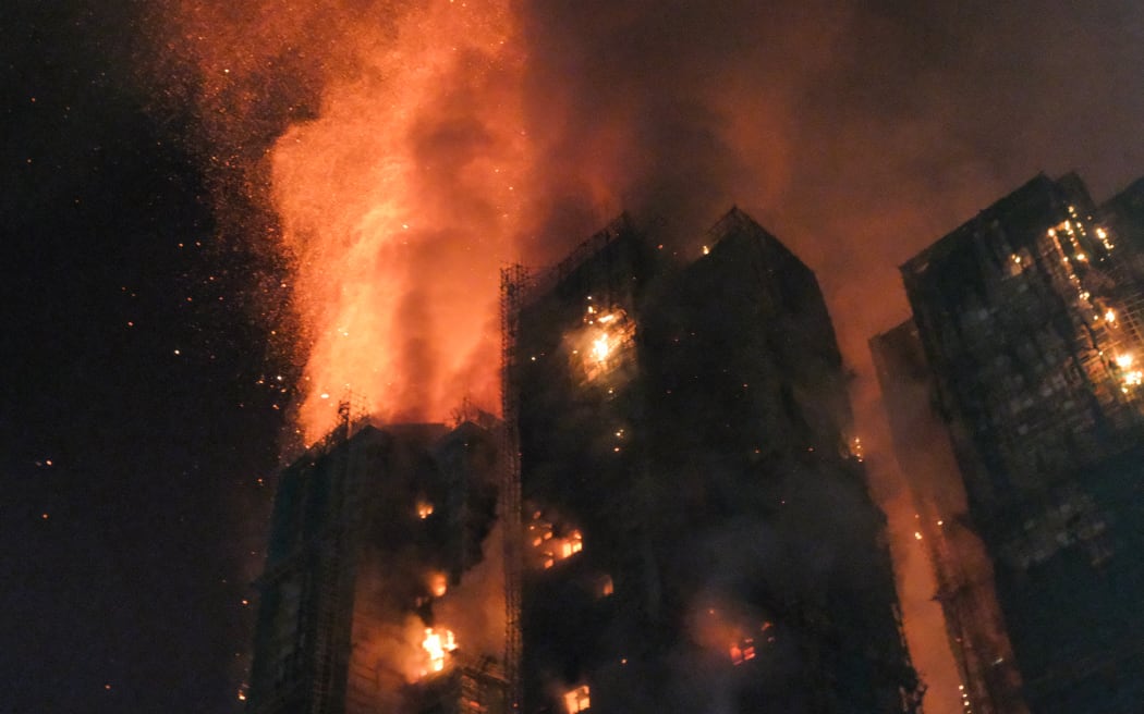 Thick smoke and flames rise as a major fire engulfs several apartment blocks at the Wang Fuk Court residential estate in Hong Kong's Tai Po district on November 26, 2025. At least four people were killed when a fire engulfed several high-rise blocks in a Hong Kong residential estate on November 26, the government said, with media reporting that some residents were trapped inside. (Photo by Tommy WANG / AFP)