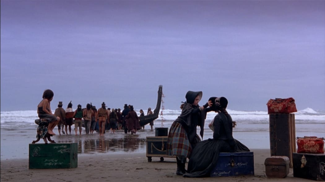 In a still image from Jane Campion's The Piano, Ada and Flora are waiting on the beach to be transported to Nelson by Māori waka.