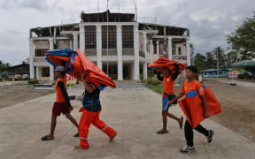 Rescue workers walk past a damaged town hall after a 6.6-magnitude earthquake hit Magsaysay, on the southern island of Mindanao, on October 29, 2019.