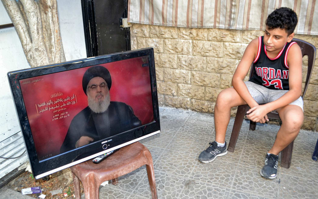 A boy sits next to a television set airing a speech by the leader of the Lebanese Shiite movement Hezbollah Hassan Nasrallah at a cafe in the Jabal Mehsen neighbourhood of Lebanon's northern city of Tripoli on September 19, 2024. Lebanon's powerful Hezbollah chief said on September 19 that Israel will not be able to return residents of the north displaced by 11 months of cross-border exchanges to their homes through military escalation. (Photo by Fathi AL-MASRI / AFP)