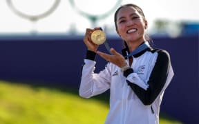 New Zealand's gold medallist Lydia Ko celebrates with her medal on the podium during the women’s golf individual stroke play medal ceremony of the Paris 2024 Olympic Games at Le Golf National in Guyancourt, south-west of Paris, on August 10, 2024. (Photo by Pierre-Philippe MARCOU / AFP)