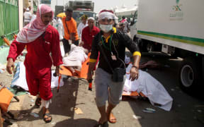 Saudi emergency personnel and Hajj pilgrims carry a wounded person at the site where hundreds were killed in a stampede in Mina, near the holy city of Mecca.