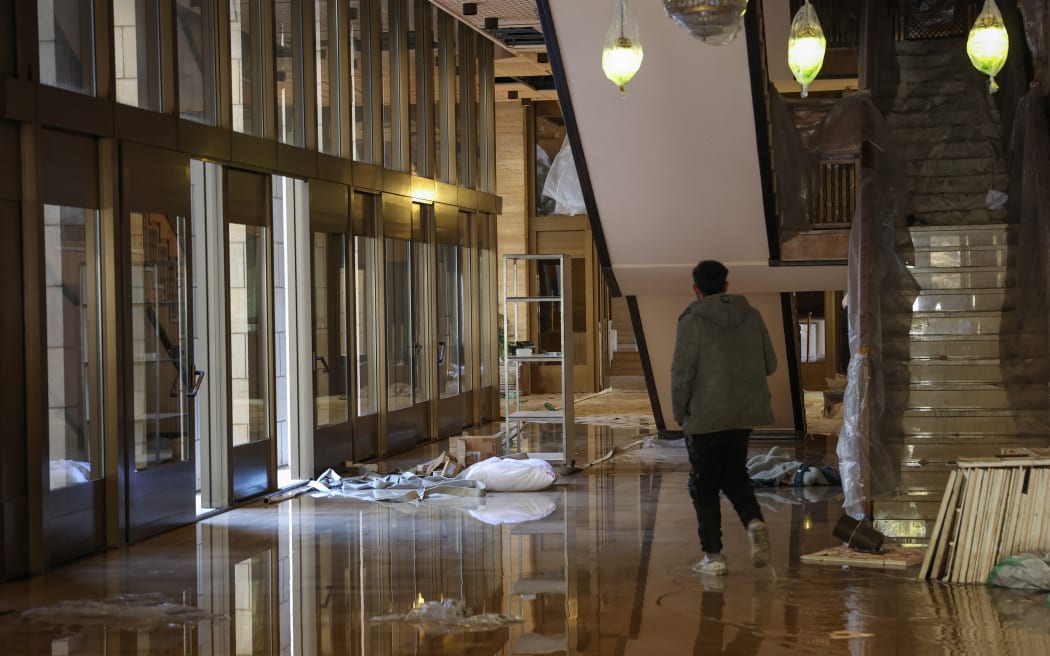 A man walks inside the Tishrin residential palace of Syria's ousted president Bashar al-Assad in Damascus' al-Muhajirin area on December 8, 2024, after Islamist-led rebels declared that they have taken the Syrian capital in a lightning offensive, sending al-Assad fleeing and ending five decades of Baath rule in Syria. (Photo by OMAR HAJ KADOUR / AFP)