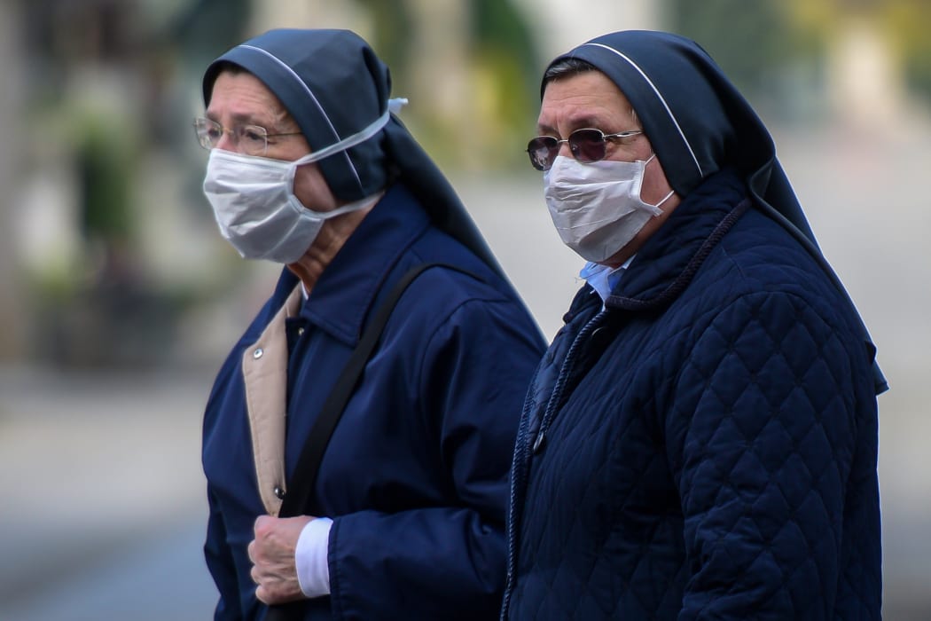 Nuns wearing face masks stand inside the closed Monumental Cemetery of Bergamo, Lombardy during the country's lockdown.