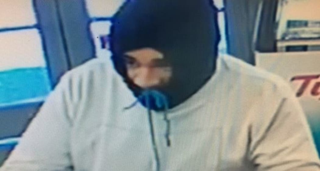 This man was wearing a grey sweat shirt with a dark coloured hood covering his face.