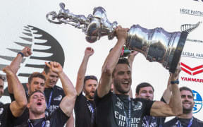 Team New Zealand flight controller Blair Tuke lifts the America's Cup.