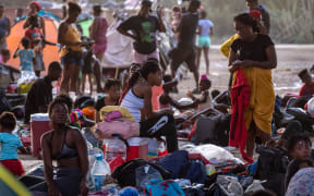 Immigrants sit and lie under the international bridge at a migrant camp on the US-Mexico border on 21 September 2021 in Del Rio, Texas. The immigrants, mostly from Haiti have numbered as high as 14,000 at the camp.