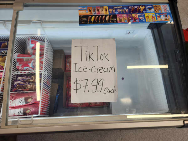 A picture of an empty freezer with a poster "TikTok Ice-Cream $7.99 each" written on it.
